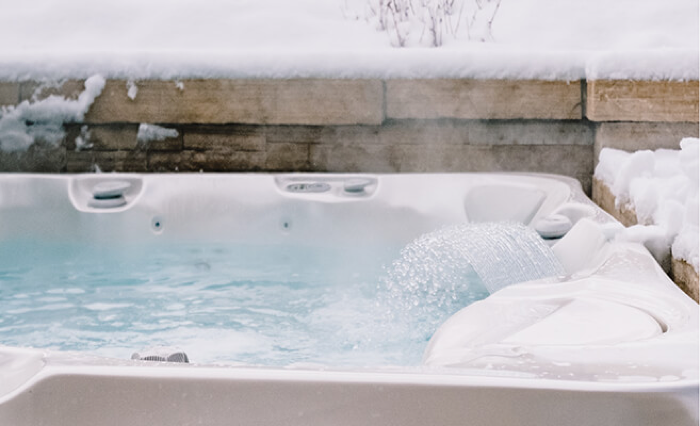 Steam rising from a hot tub's water with snow on the surround