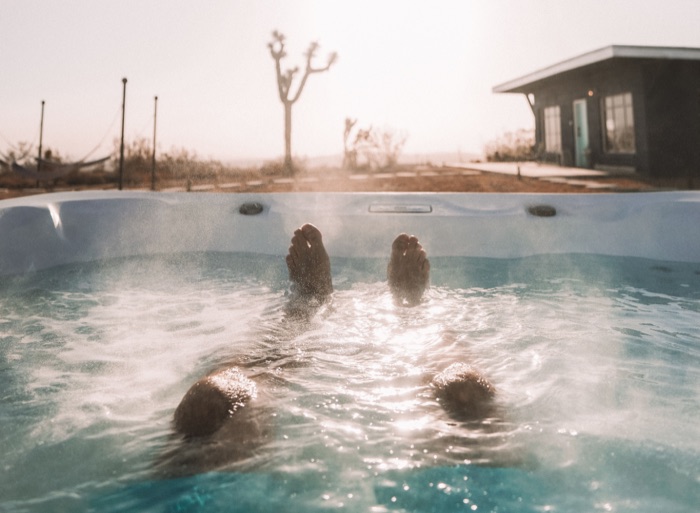 Two people relaxing with their feet up in a hot tub at sunset