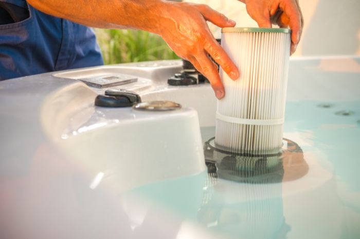 A person lifting out a hot tub filter cartridge for cleaning