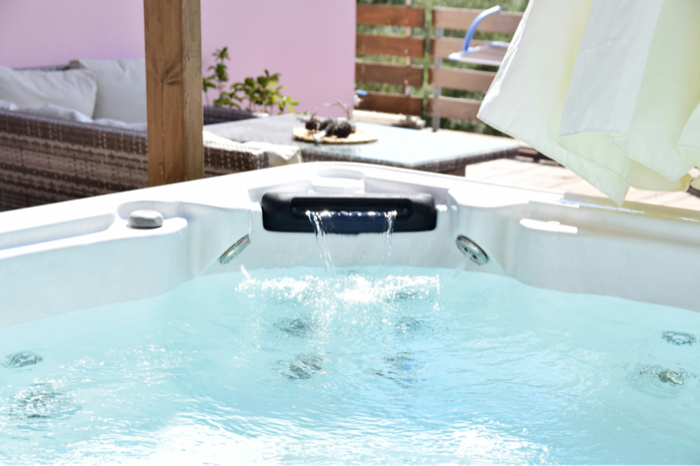 Water spilling from a hot tub's feature into clear blue water on a patio